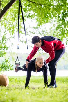 Man and woman at fitness training doing push-ups in park