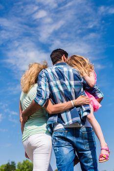 Family, hugging, backs to camera, slight low angle shot