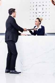 Job Applicant at business front desk giving his documents to receptionist