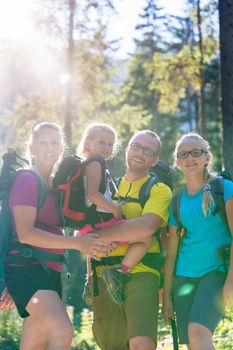 Family with two daughters on hike in the woods backlit in summer