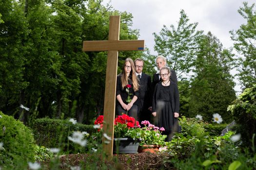 Family mourning at grave on graveyard or cemetery