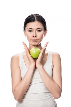 Thoughtful young Asian woman holding a green apple against white background