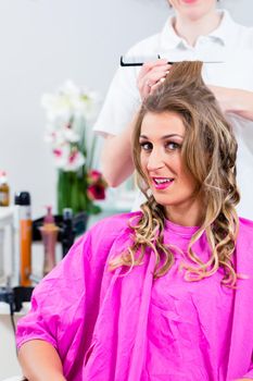 Customer at hairdresser with hair spray in salon receiving hairdo