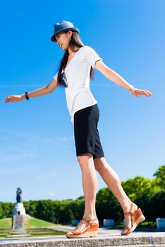 Low-angle view of young Asian woman standing on one leg outdoors in summer