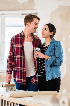 Portrait of a happy young couple wearing casual clothes while holding tools for home remodeling after moving in together