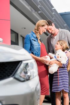Mother, father, and child buying car at dealership, a new family auto