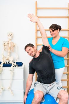 Young man does stretching exercises with physiotherapist