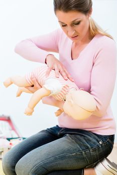 Woman in first aid course practicing revival of infant on baby doll