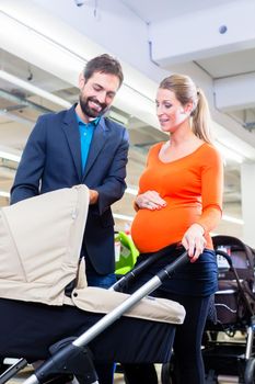 Couple in baby shop buying stroller, the woman in pregnant