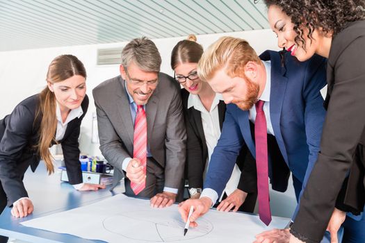 Group of business people are leaning over a desk and analyze graphs