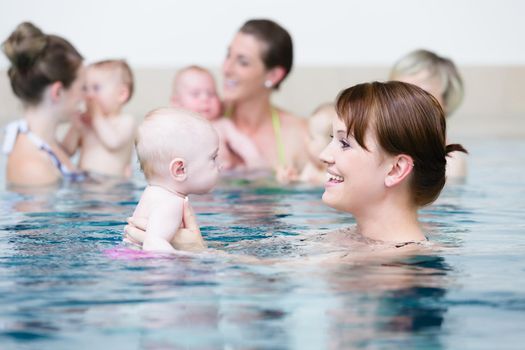 Group of mums with their baby children at infant swimming class