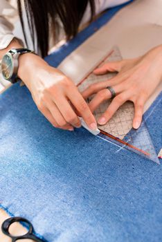 Detail of hands with scissors at tailor shop cutting cloth