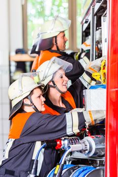 Fire fighters attaching hose at hose laying vehicle