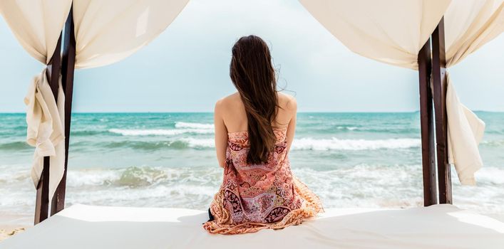 Woman sitting in beach bed looking at the sea, serene scene
