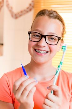 Teenager girl with dental braces brushing her teeth