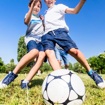 Happy family playing football in park in summer