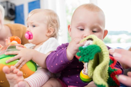 Babies with pacifier in toddler group playing with toys