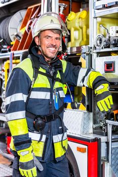 Fire fighter in uniform leaning at vehicle of fire department