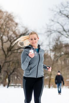 Woman running or jogging down a path on winter day in park