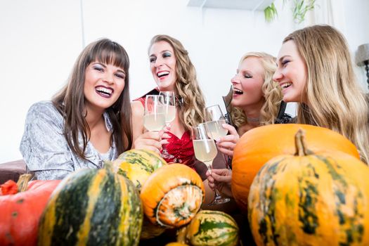 Young and beautiful woman posing funny and scary while toasting with her best friends during Halloween costume party