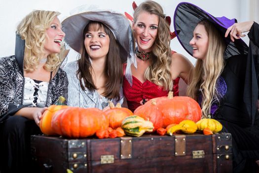 Three young and beautiful women wearing funny party costumes while acting as witches joining their malicious forces at Halloween