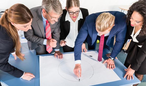 Group of business people are leaning over a desk and analyze graphs