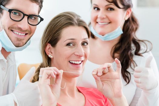 Woman at dentist using dental floss, the doctor explaining proper use