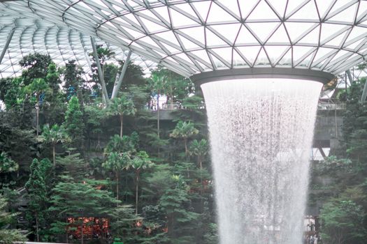 SINGAPORE - 21 DEC 2019: Rain Vortex the largest indoor waterfall located in Jewel Changi Airport with MRT and Tourists.