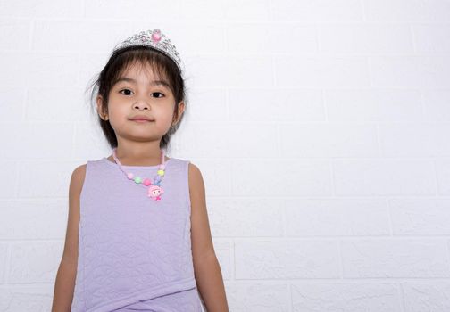 Female asian child girl standing with white background wearing accessories, crown and necklace with purple dress