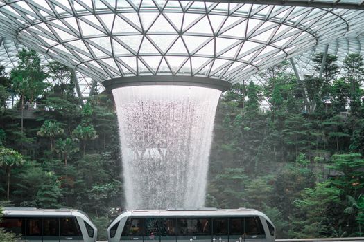 SINGAPORE - 21 DEC 2019: Rain Vortex the largest indoor waterfall located in Jewel Changi Airport with MRT and Tourists.