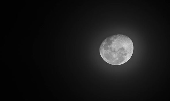 Moon through telescope with visible craters and the sea of tranquility. Black and white photo of moon in close up