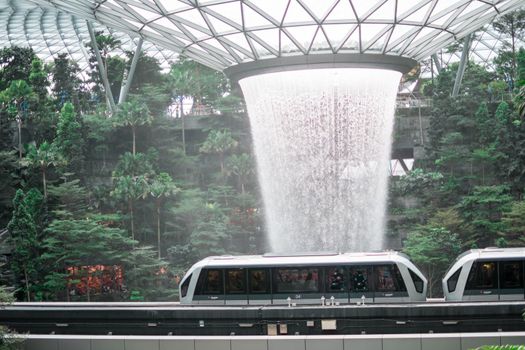 SINGAPORE - 21 DEC 2019: Rain Vortex the largest indoor waterfall located in Jewel Changi Airport with MRT and Tourists.