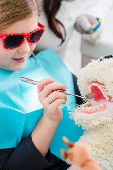 Child at dentist office looking after teeth of pet toy