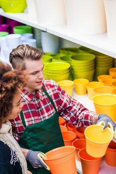 High-angle view of a beautiful customer buying plastic pots at the advice of a handsome and helpful worker in a modern flower shop