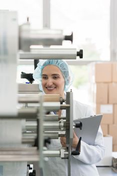 Female manufacturing supervisor looking worried while checking equipment and production during quality control in the interior of a cosmetics factory