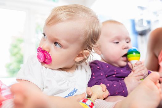Babies with pacifier in toddler group playing together with toys