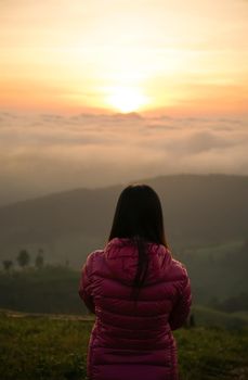 woman watching sunrise alone at hilltop