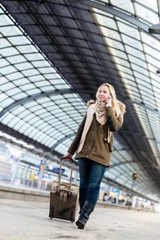 Woman with her luggage walking along the platform in train station after arriving