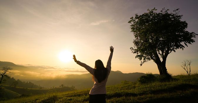 Happy woman enjoying life at sunrise in mountains