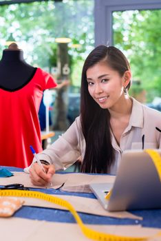 Asian fashion designer preparing drafts for cut-outs for her new collection