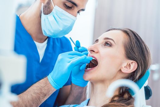 Side view of a young woman during painless teeth cleaning done in a modern medical center