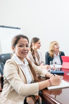 Portrait of a confident Asian business woman wearing formal outfits, while sitting down during a decision-making meeting in the conference room of a successful company