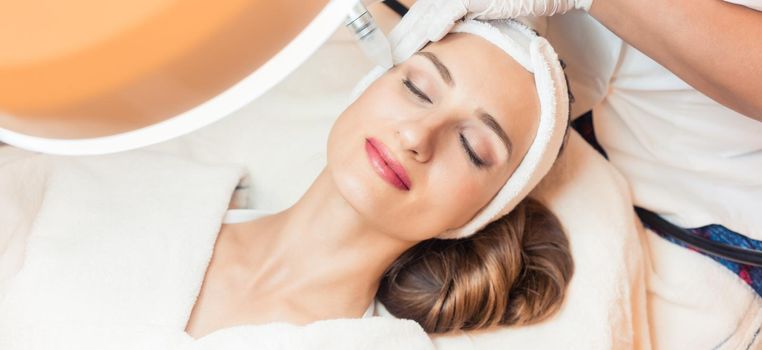 Close-up of the face of a woman relaxing in a modern beauty center during facial treatment with innovative technology for softening wrinkles and rejuvenation