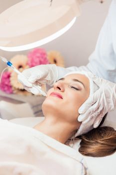 Beautiful woman relaxing during non-invasive facial treatment for rejuvenation in a contemporary beauty center with innovative equipment