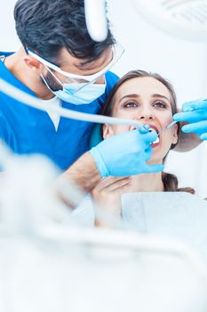 Beautiful young woman looking up relaxed during a painless dental procedure, done by her reliable dentist in a modern clinic with sterile equipment