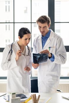 Two young dedicated doctors analyzing together the radiograph of the leg of a patient in a modern hospital