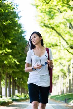 Serene beautiful young woman smiling while walking in the park in summer