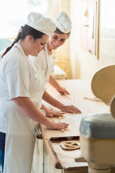 Baker women working in bakehouse of bakery looking into camera