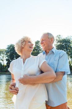 Low-angle side view portrait of a romantic senior couple in love enjoying a healthy and active lifestyle outdoors in summer