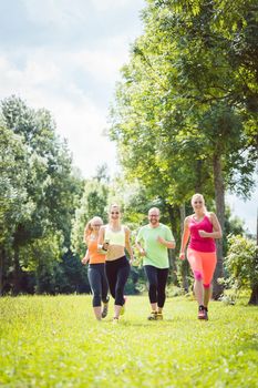 Family with personal Fitness Trainer jogging on a meadow